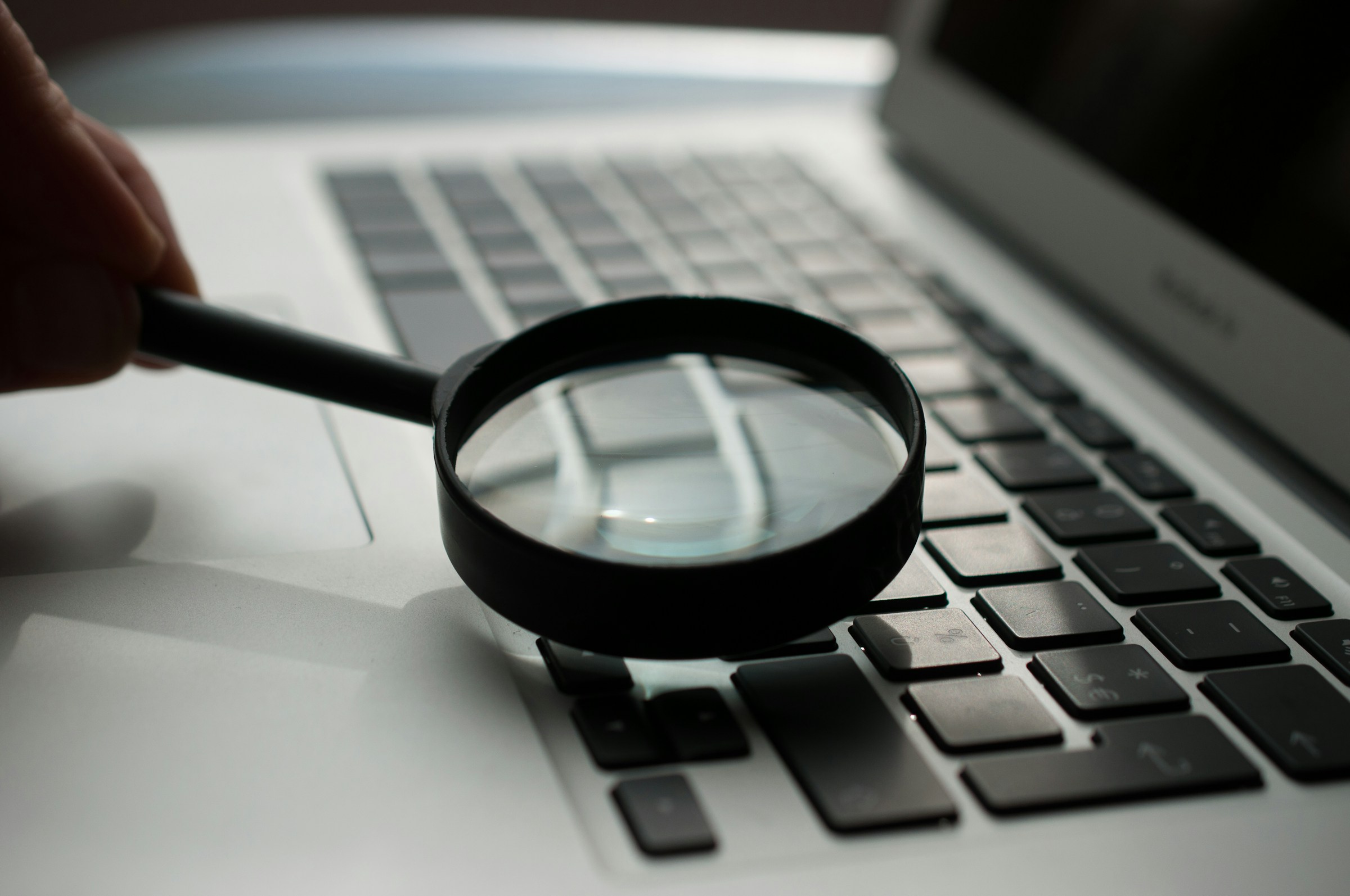 Magnifying glass placed on a laptop keyboard for search concept